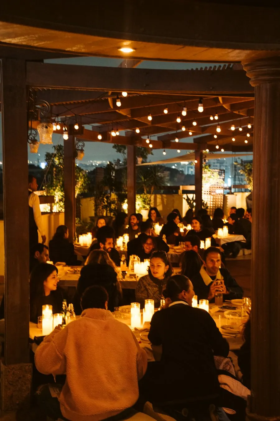 A candlelit Big Belly dinner on a Cairo rooftop, long tables full of guests under string lights