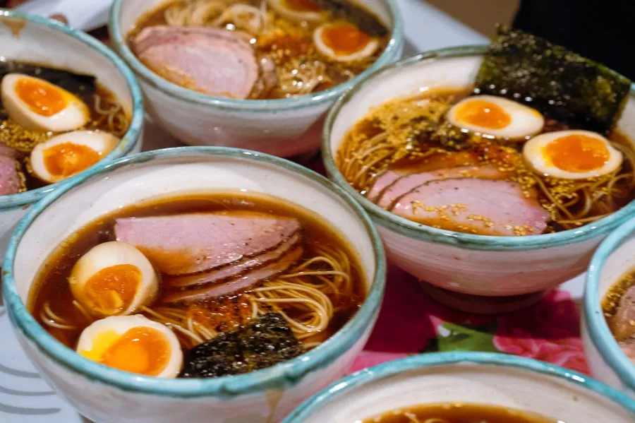 Bowls of ramen with soft eggs and sliced meat, ready to go out